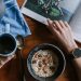 A person having tea and cereal while reading a magazine.
