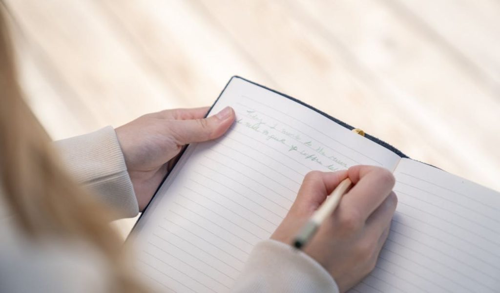 A person writing in an open notebook.