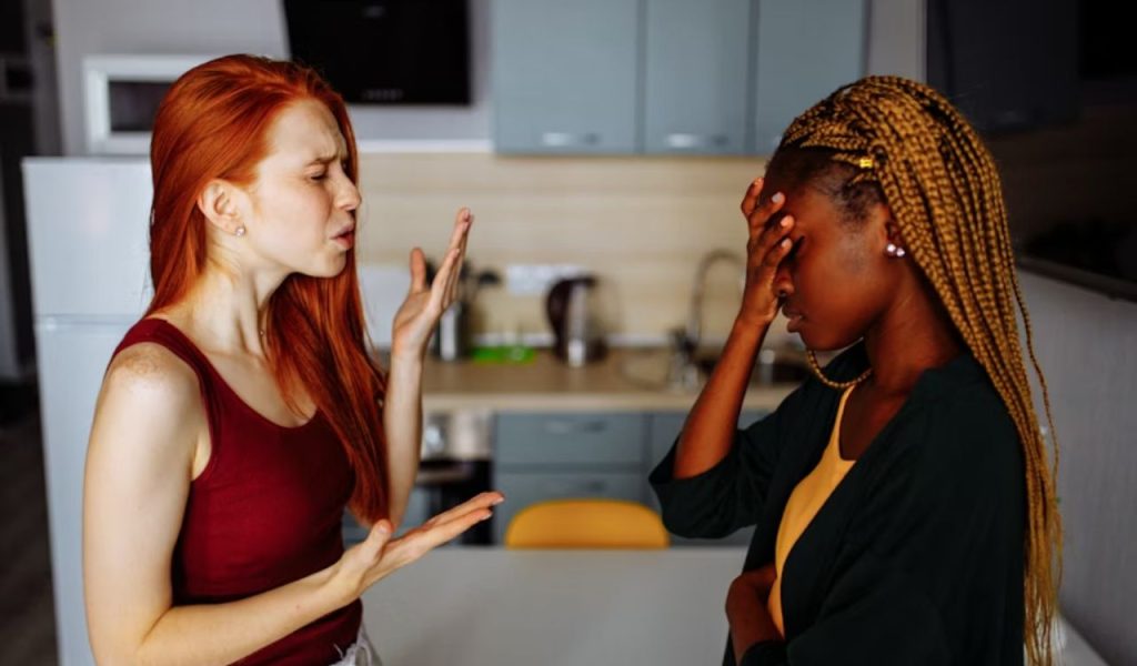 Two people arguing, with one looking frustrated and holding her forehead.