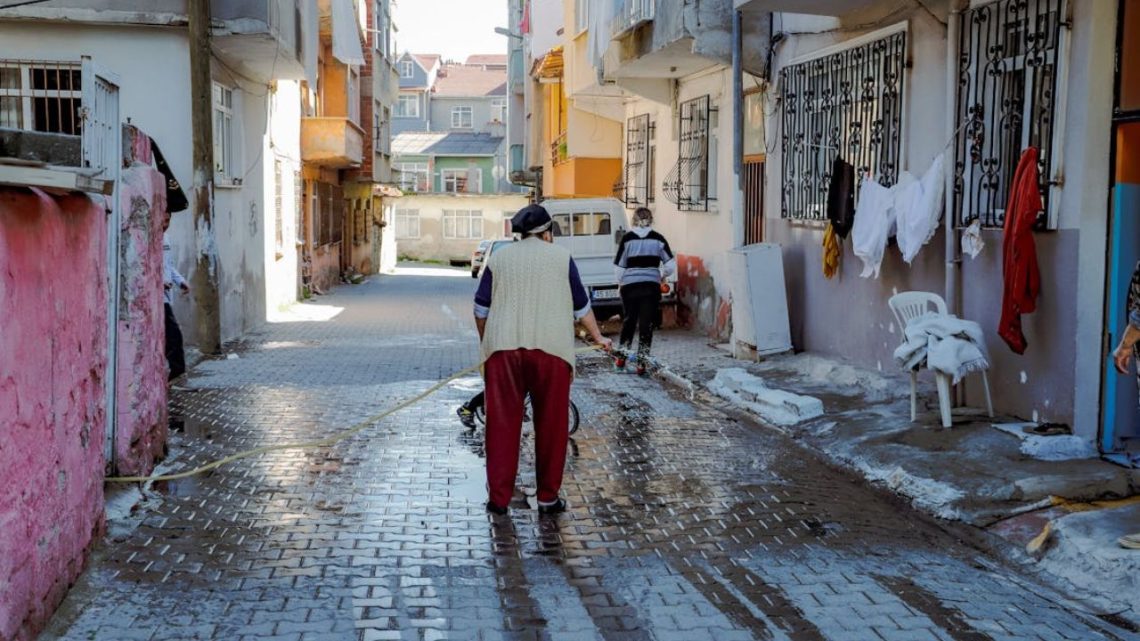 People washing a narrow residential street.
