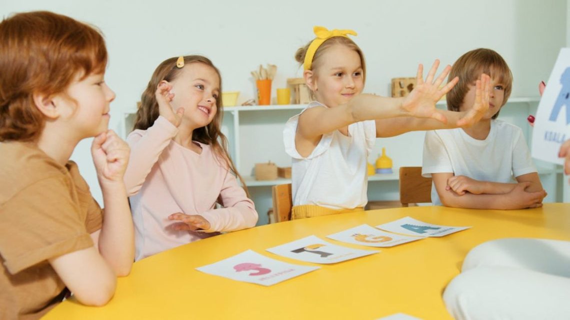 Children in a classroom raising hands during an activity.