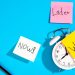 Alarm clock with sticky notes reading “Now,” “Later,” and “Work.”