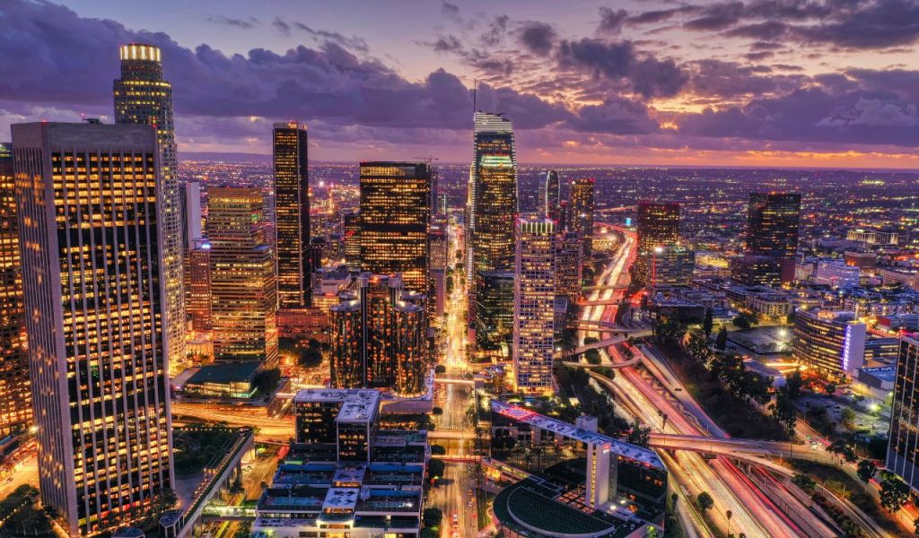 Skyline at dusk with glowing city lights and freeways.