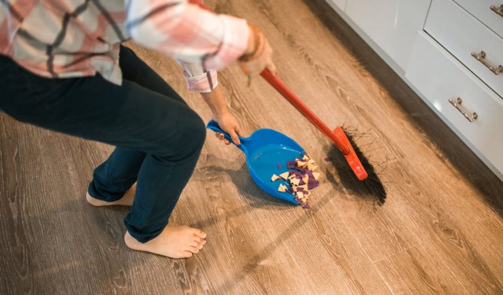 Person sweeping debris into a dustpan.