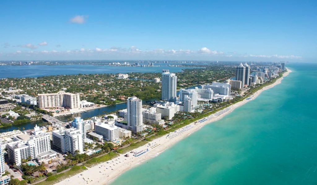 Aerial view of beachfront high-rises and turquoise ocean.