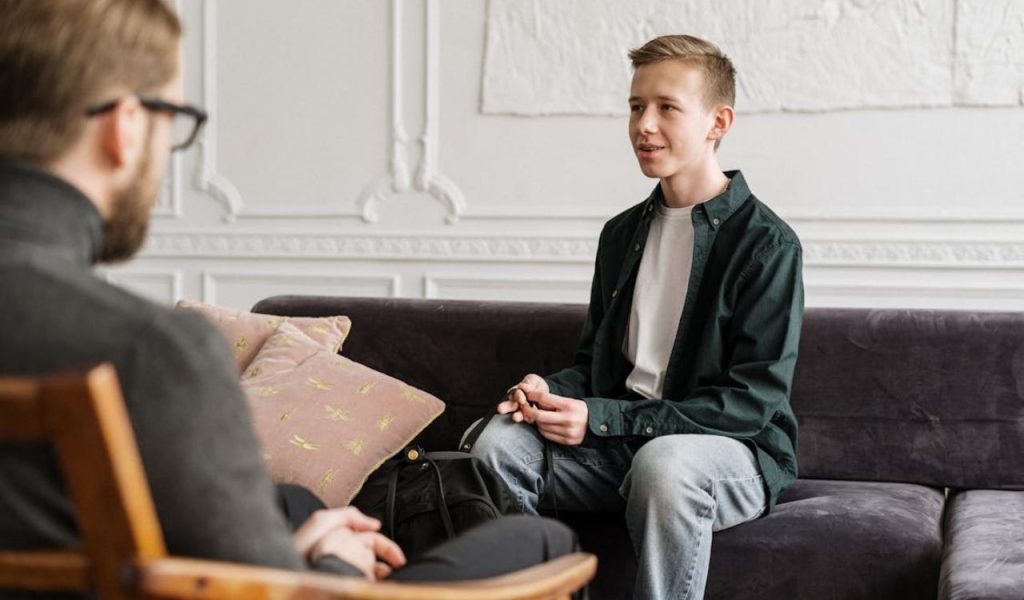 Teen talking with a counselor on a sofa.