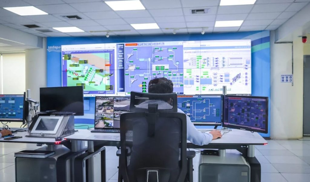 Operator monitoring multiple control screens in a control room.