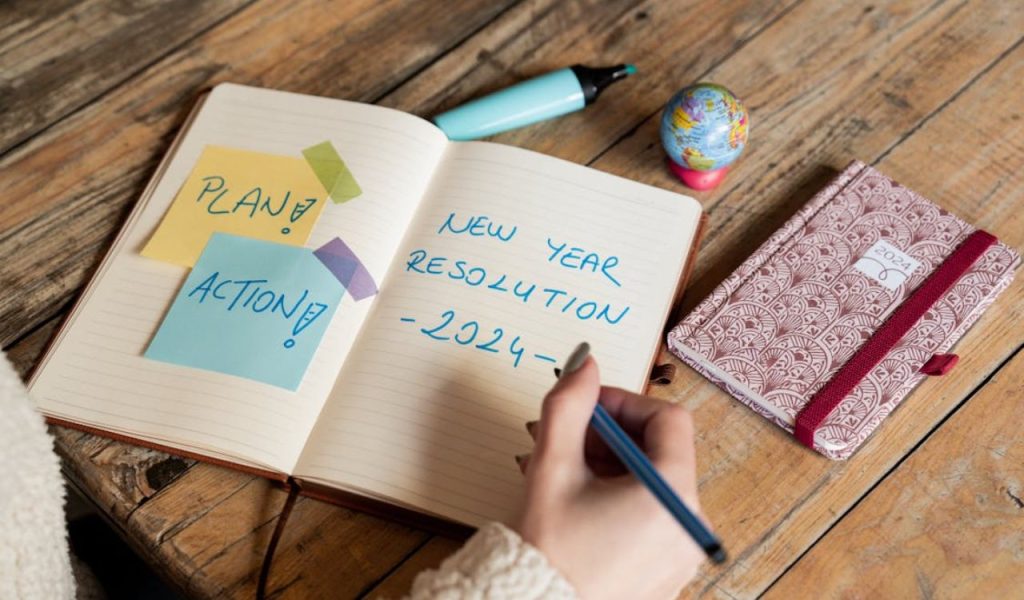 Hand writing “New Year Resolution 2024” in a notebook.