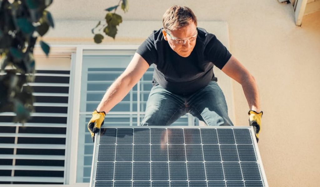 Person installing a solar panel outdoors.