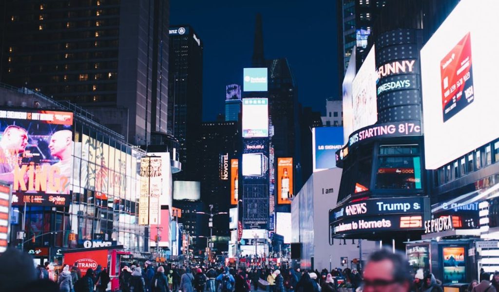 Times Square at night with bright billboards and crowds.