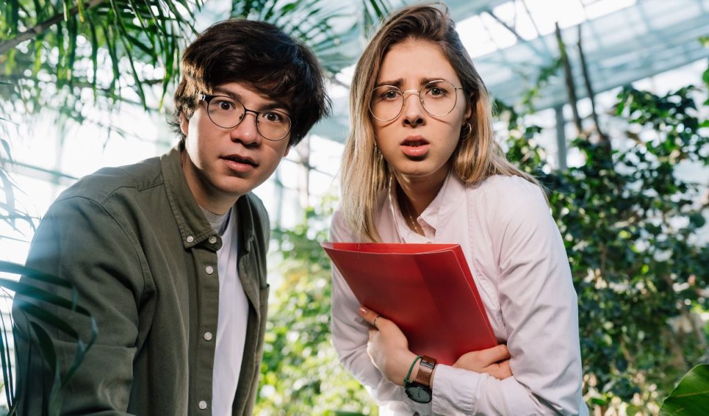 Two concerned people with glasses; one holds a red folder.