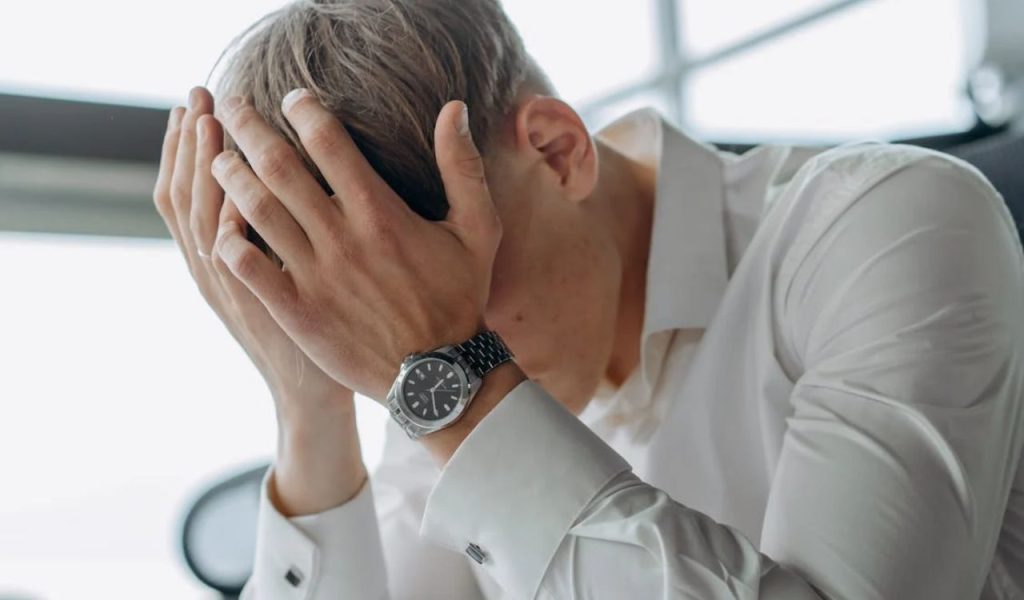 Stressed man with head in hands.