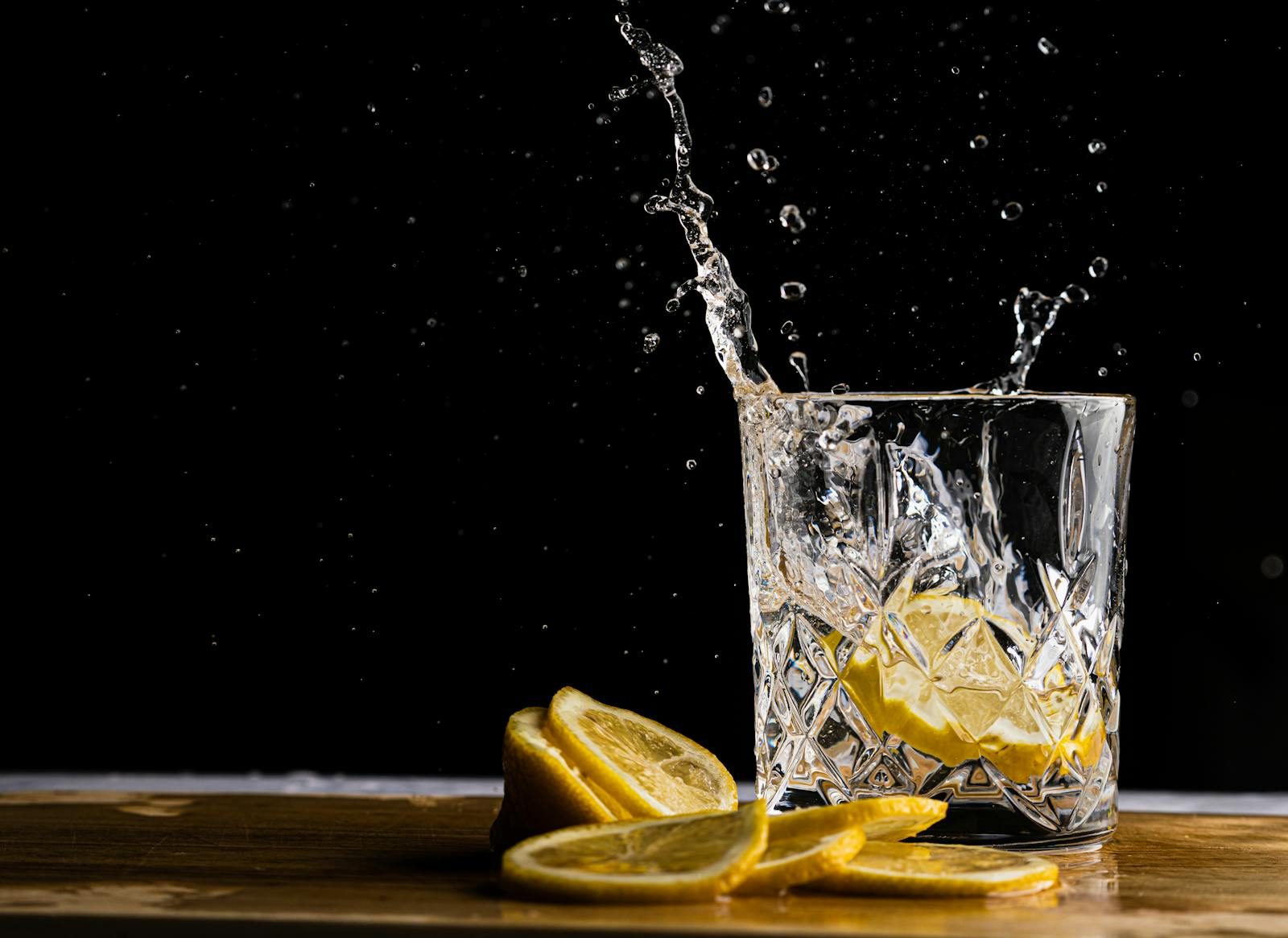 Close-up shot of lemon slices splashing in a crystal glass with a dark background.