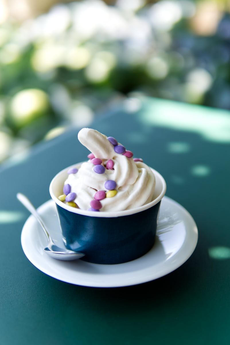 Close-up of a creamy ice cream sundae in a cup with colorful candies on top.