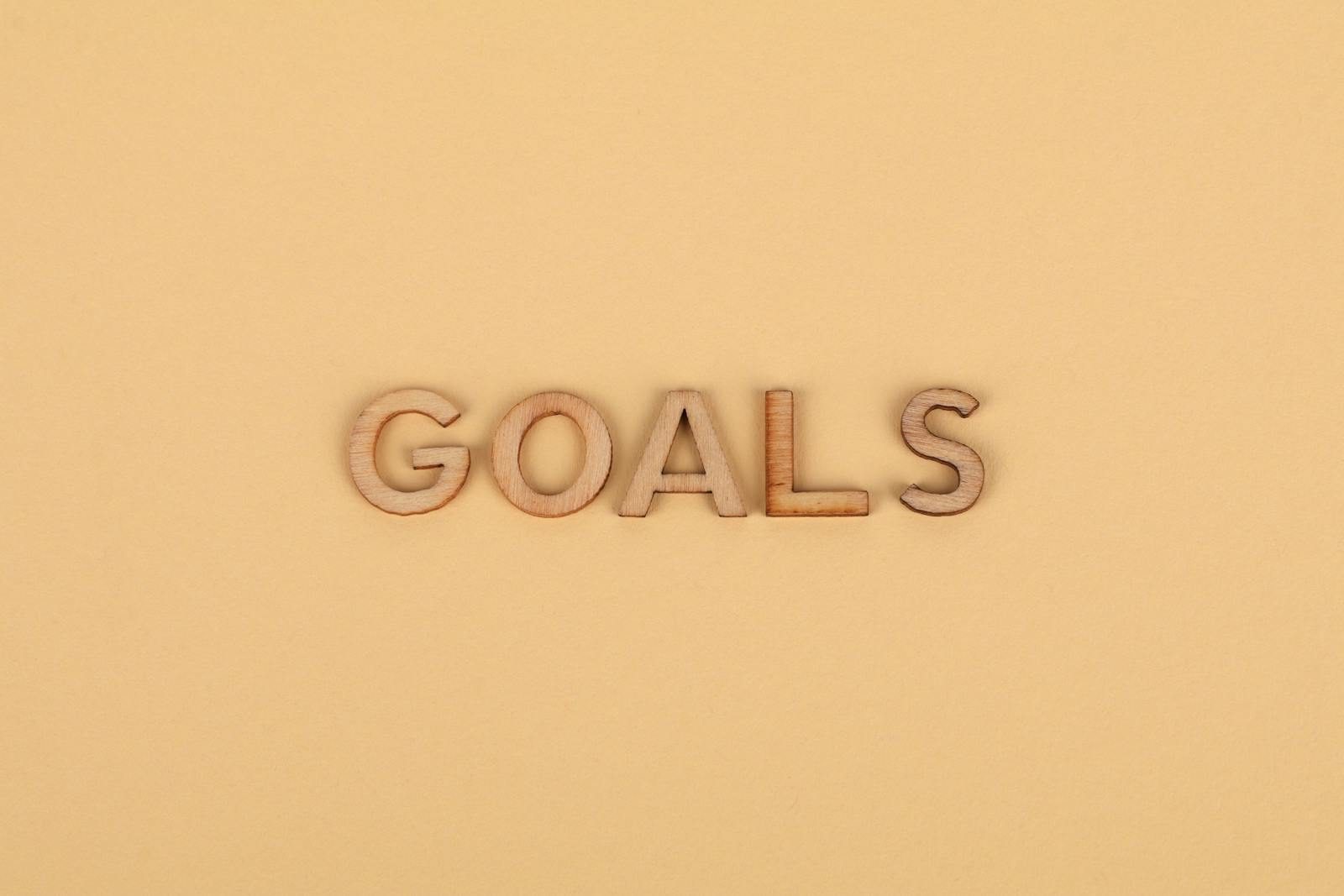 Wooden letters spelling 'GOALS' on a plain background, emphasizing motivation.
