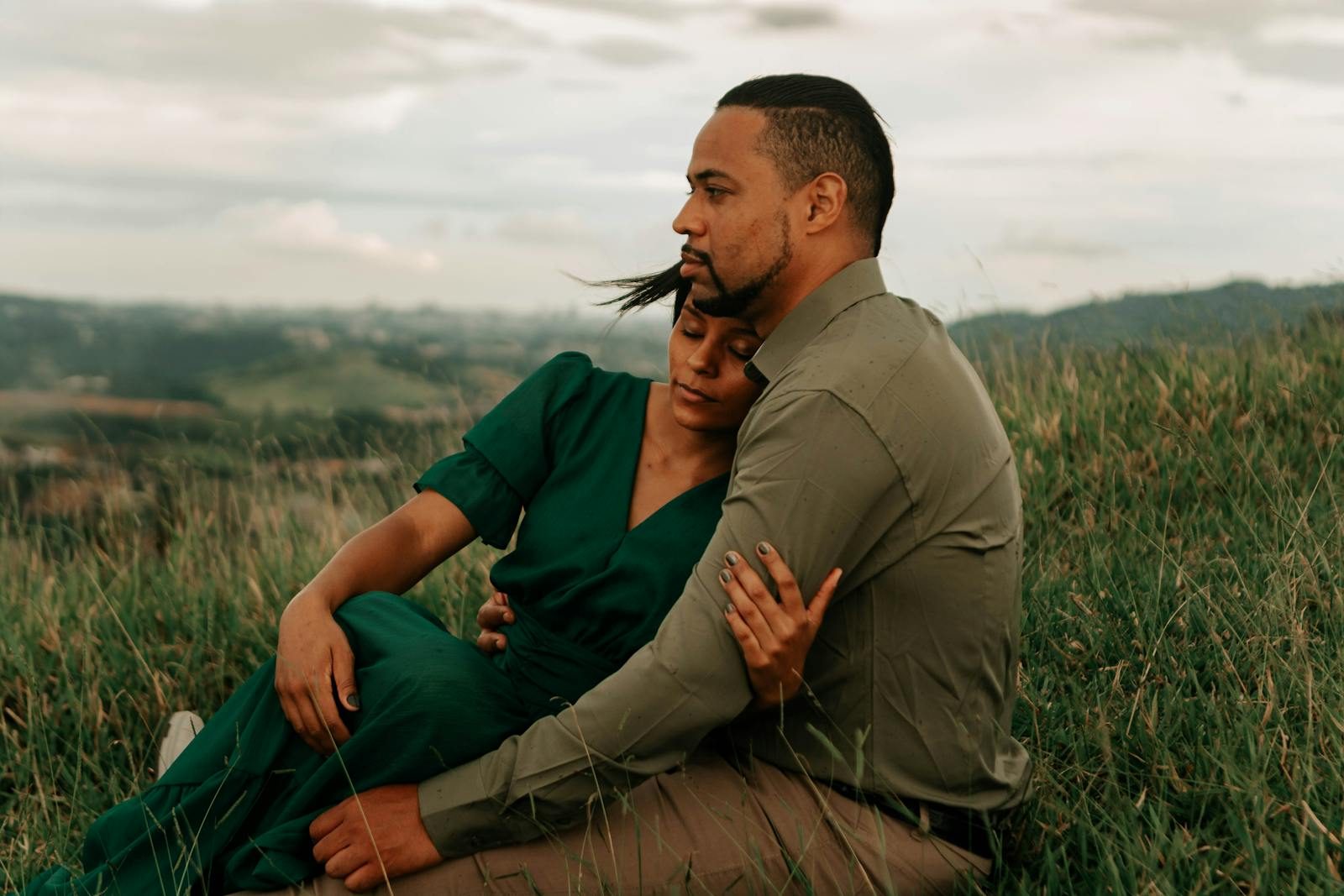 A couple embraces lovingly in a serene meadow landscape, capturing a moment of romance.