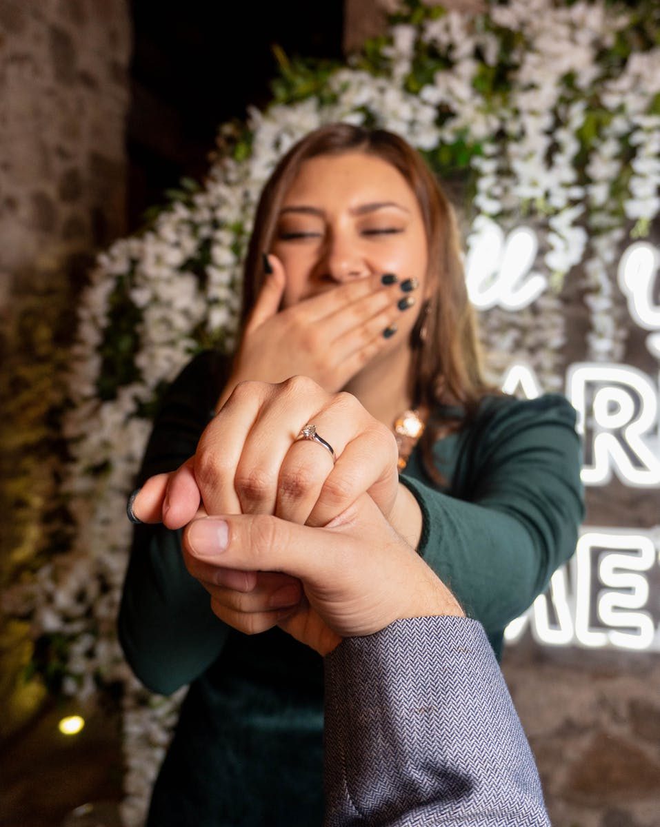 Close-up of an engagement ring on a woman's finger, evoking emotions and surprise.
