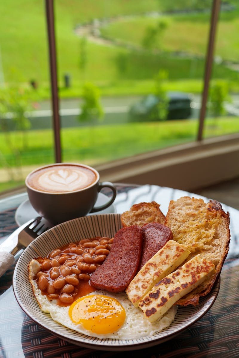 Delicious English breakfast with beans, toast, and coffee by a window with a scenic view.