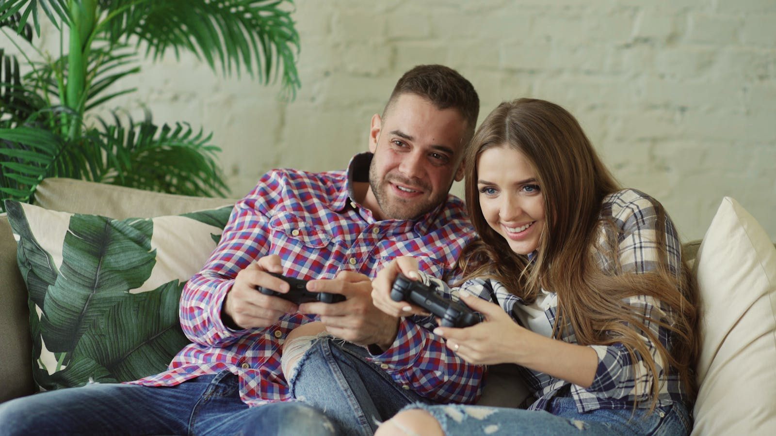 Happy couple enjoying video games together at home on a cozy sofa.