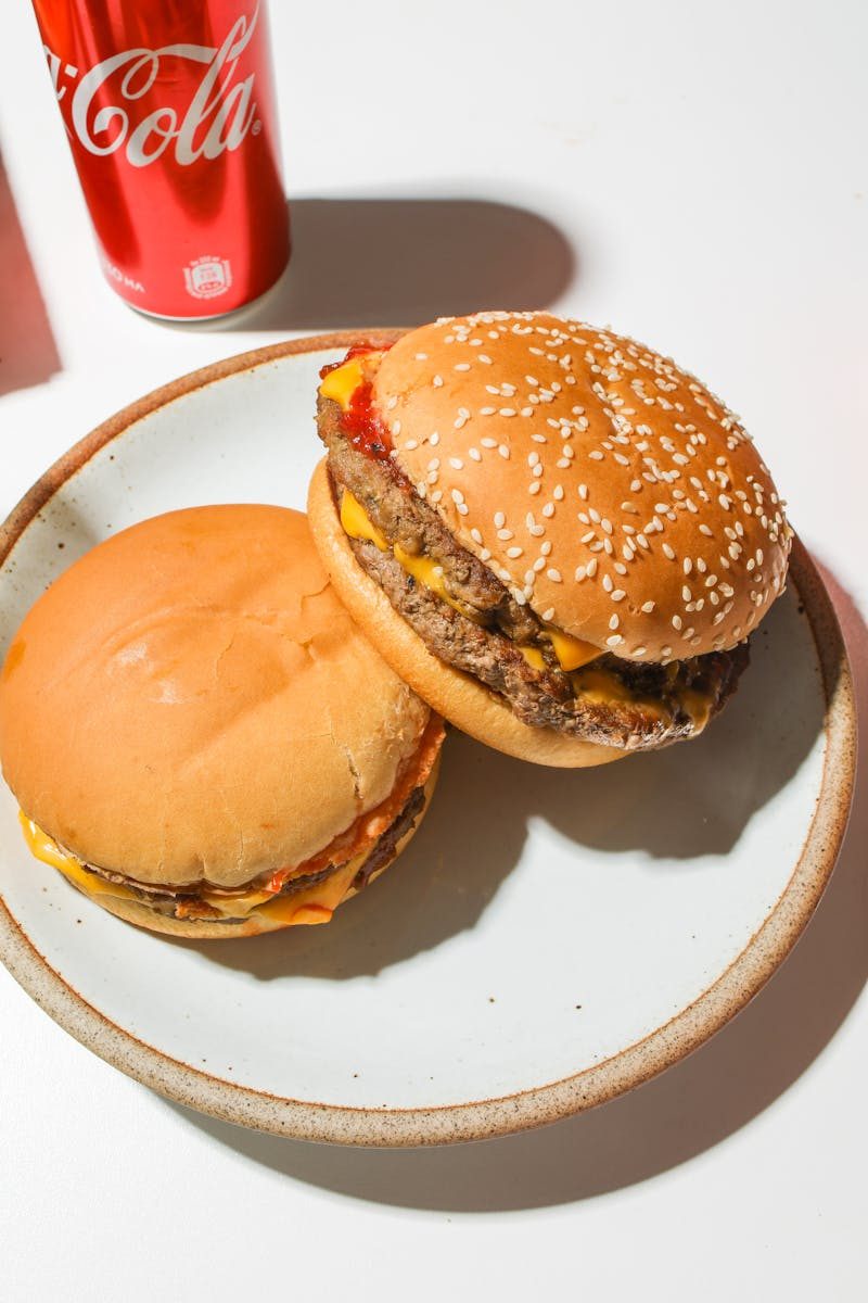 Two cheeseburgers with a Coca-Cola can on a plate, perfect fast food meal.