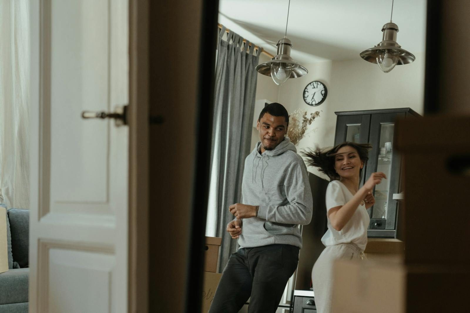 A joyful couple dances in their new apartment after relocation, celebrating a new beginning in life.