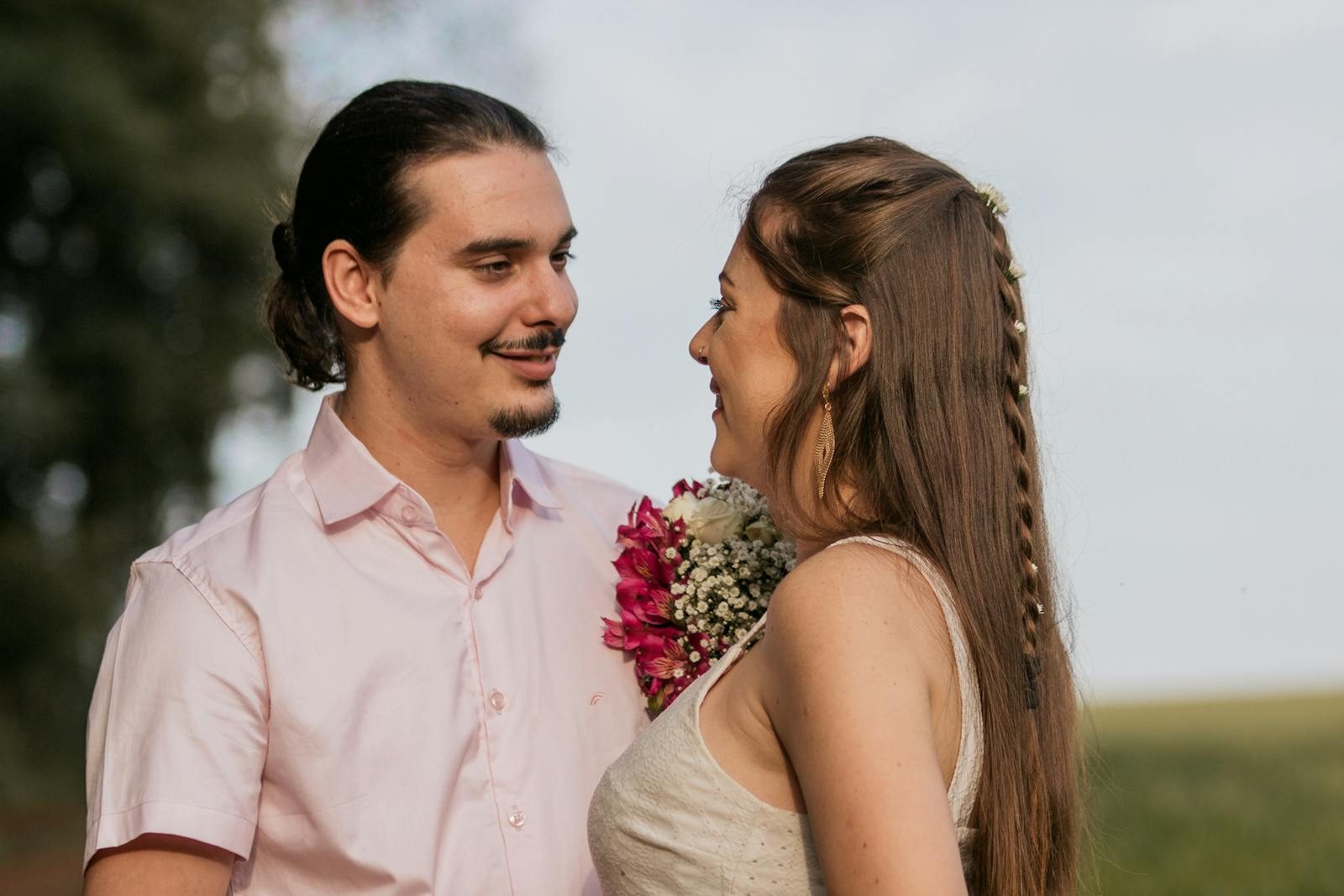 Close-up of a smiling couple with flowers, enjoying a moment together outdoors.