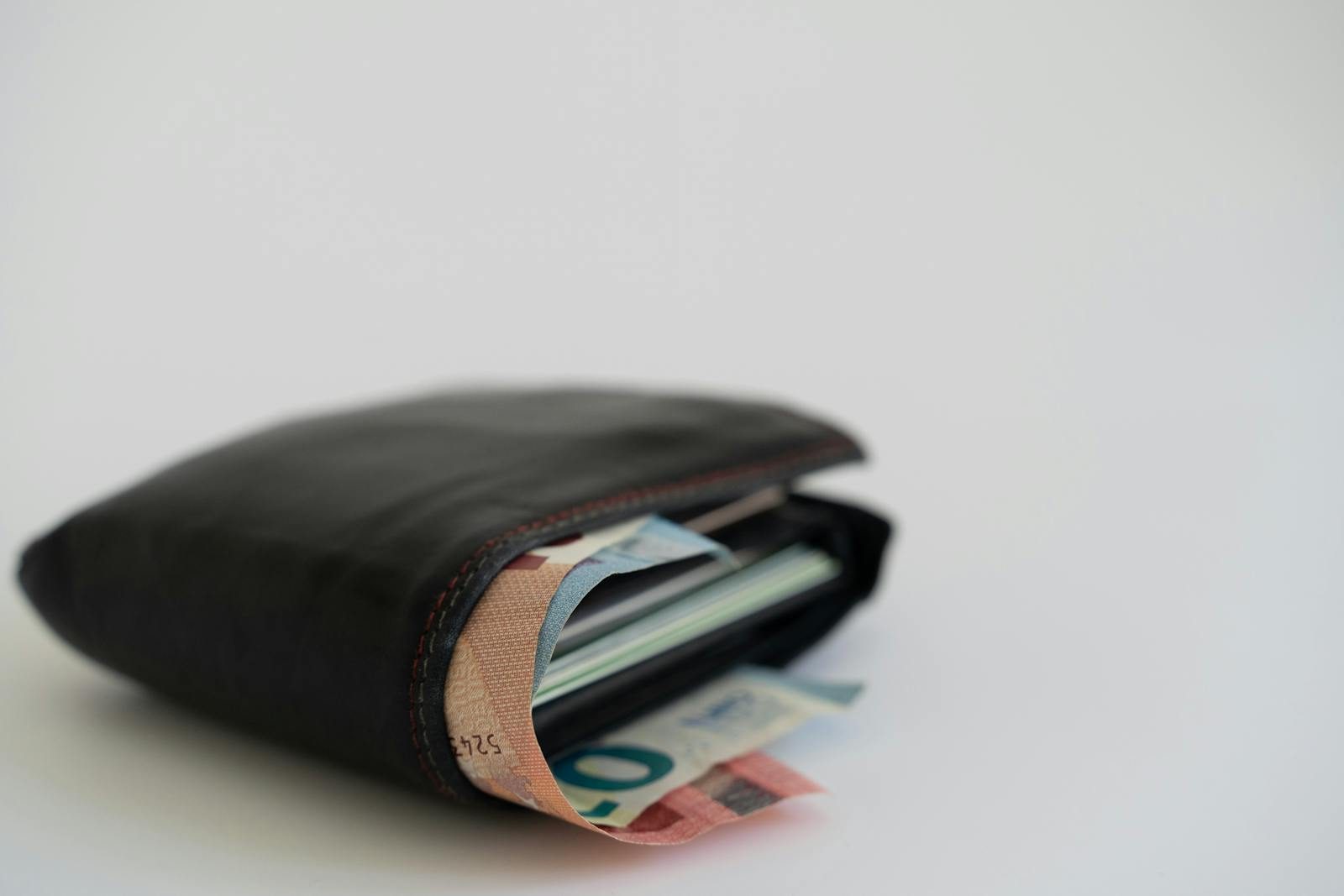 Close-up of a leather wallet filled with Euro banknotes on a white background, perfect for financial and lifestyle themes.