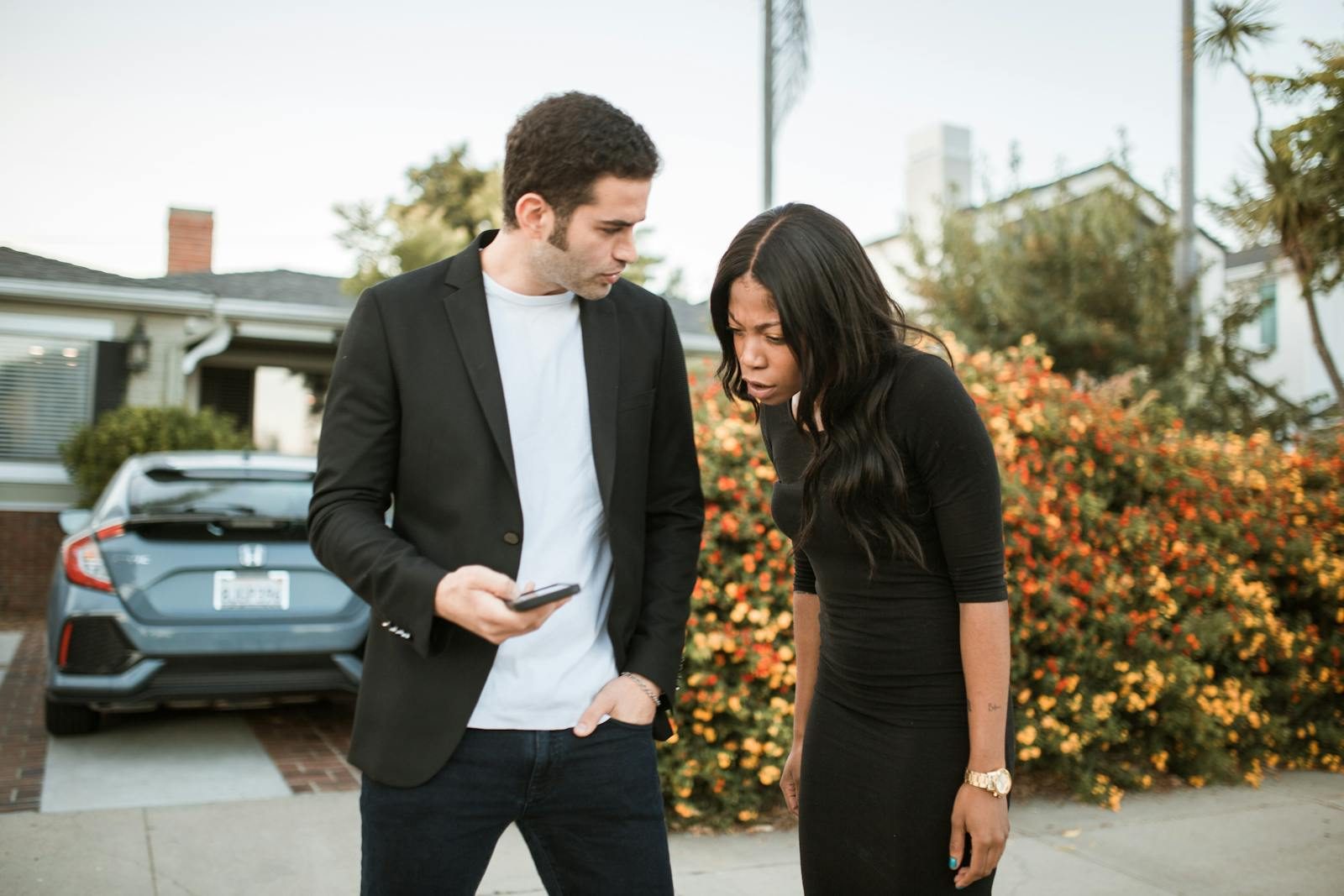 Casual scene of an interracial couple interacting with smartphones outdoors.