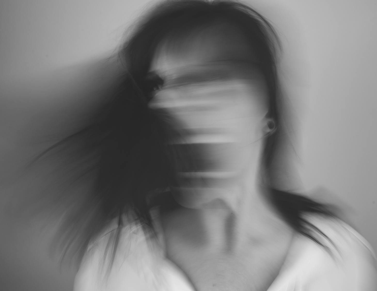 An abstract black and white portrait capturing motion blur of a person in expressive movement.