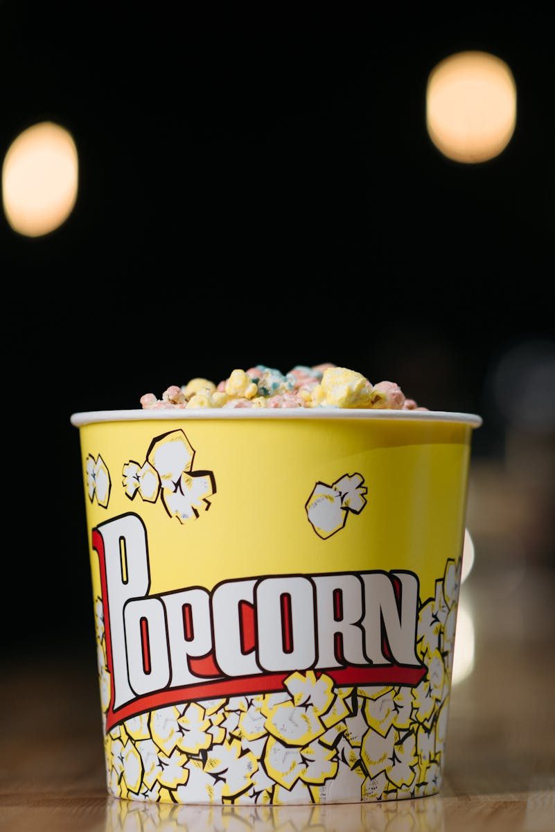 Close-up of colorful popcorn in a bright yellow bucket with a popcorn design.