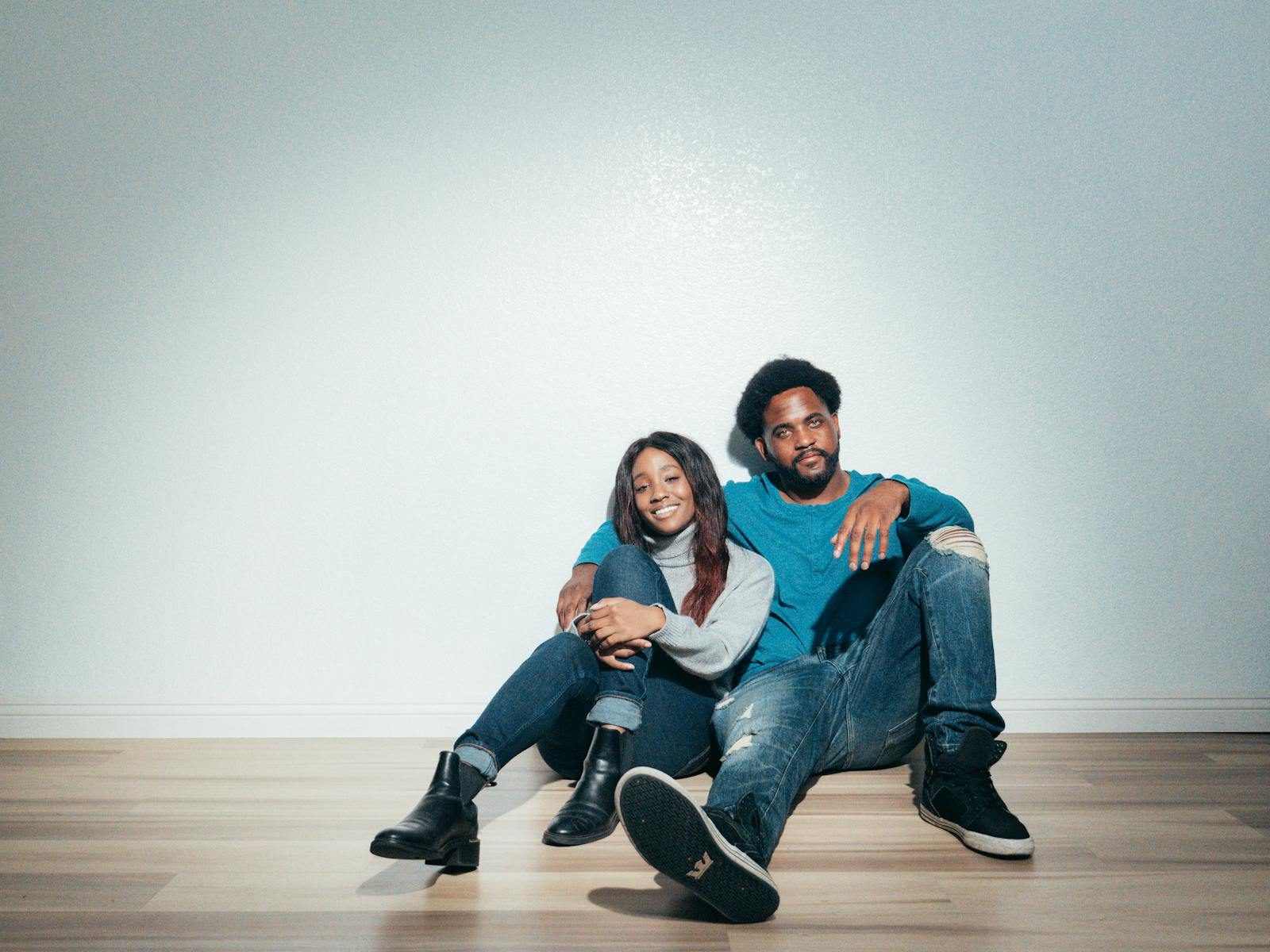 Smiling couple sitting on the floor of their new home, embracing future possibilities.