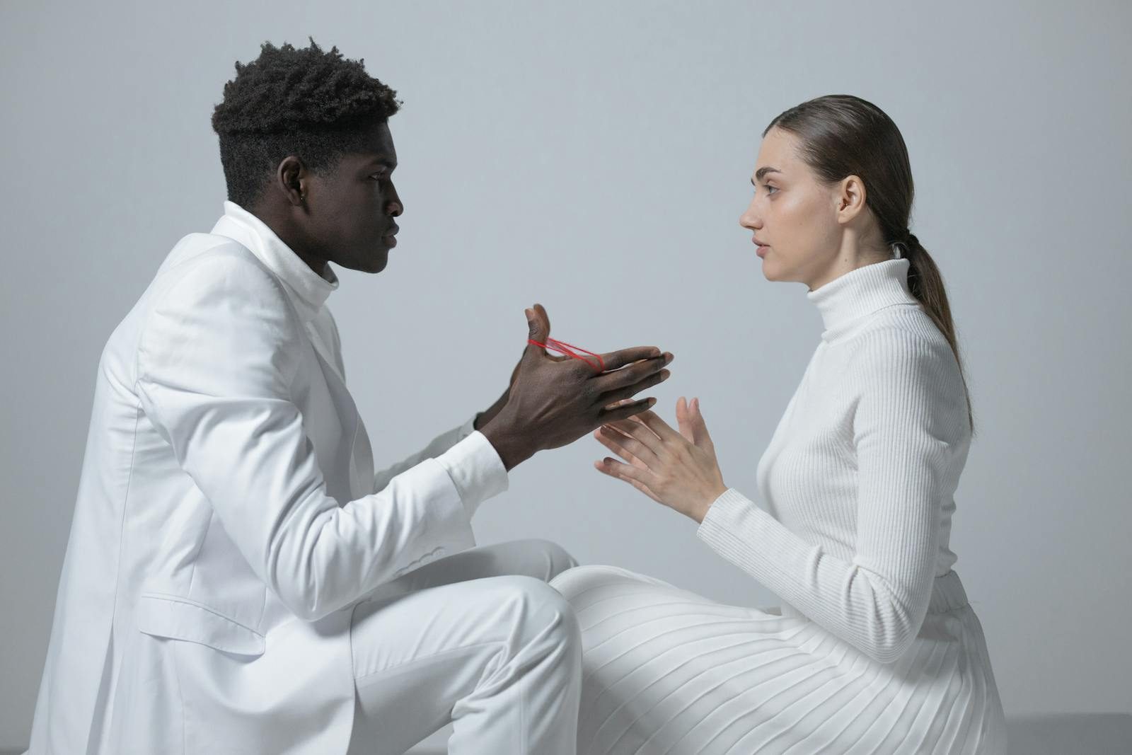 Two people in white outfits engage in conversation indoors; minimalism theme.