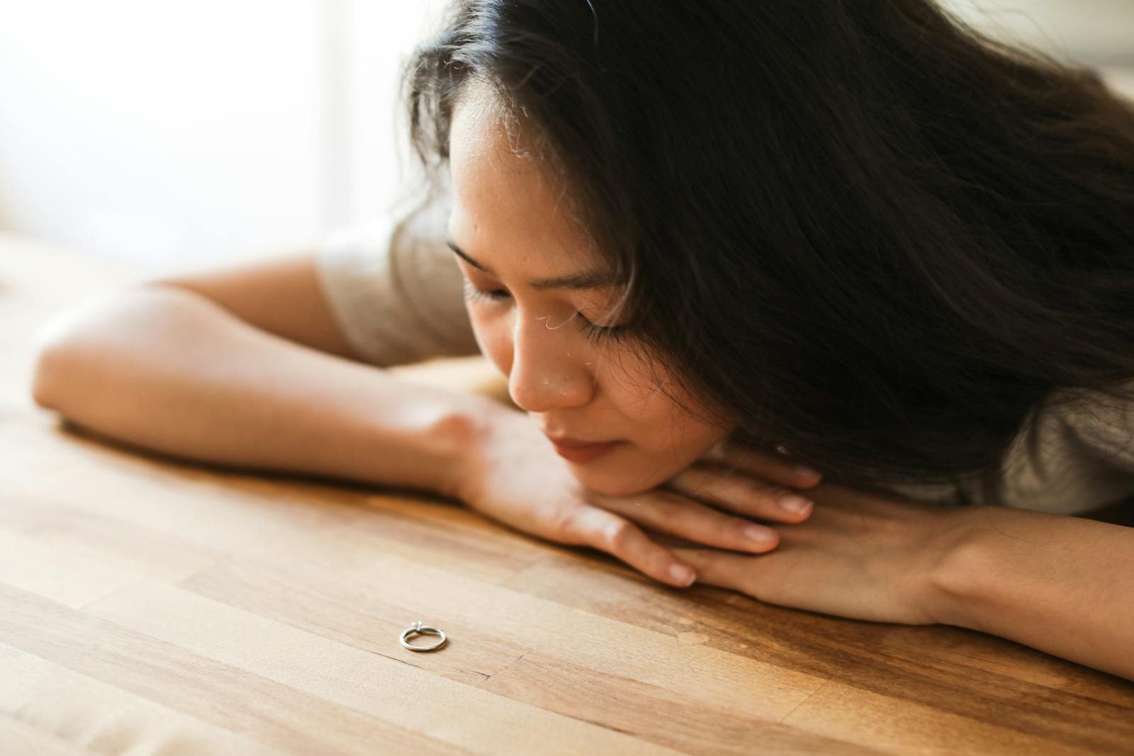 Woman gazing at a wedding ring, contemplating relationship decisions.