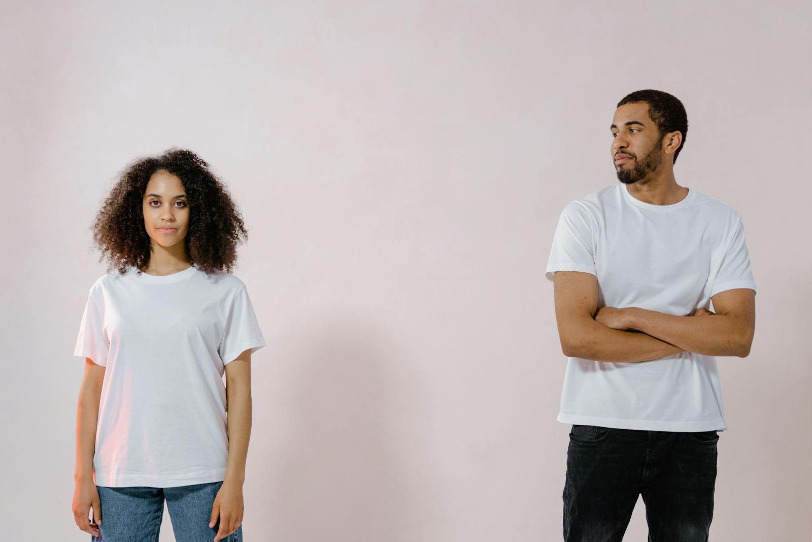 Studio portrait of an African American man and woman in casual white t-shirts looking at each other.