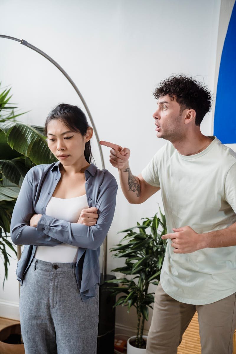 A man and woman engaging in a heated discussion at home, surrounded by indoor plants.