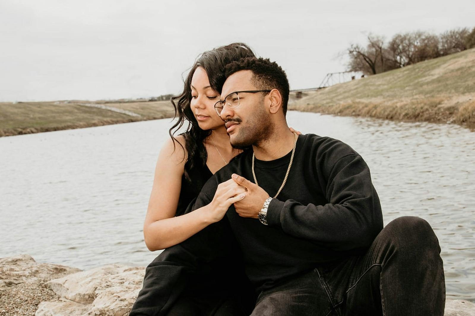 Couple enjoying a tender moment outdoors by a serene lake, showcasing love and togetherness.