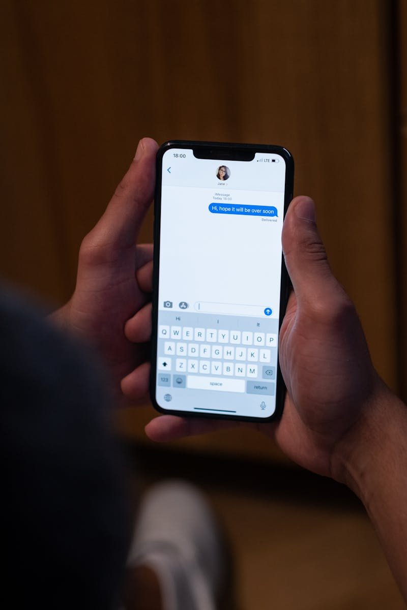 Close-up of hands texting on a smartphone indoors, showcasing modern communication.