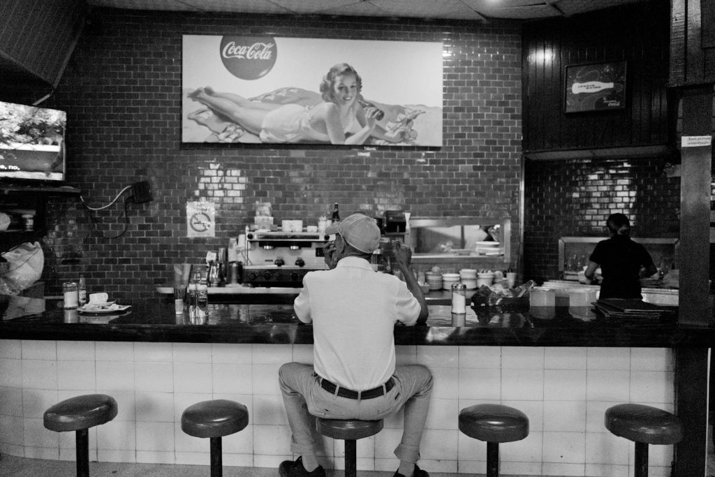 Black and white photo of a man sitting at a bar in Panama, capturing a nostalgic atmosphere.