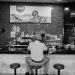 Black and white photo of a man sitting at a bar in Panama, capturing a nostalgic atmosphere.