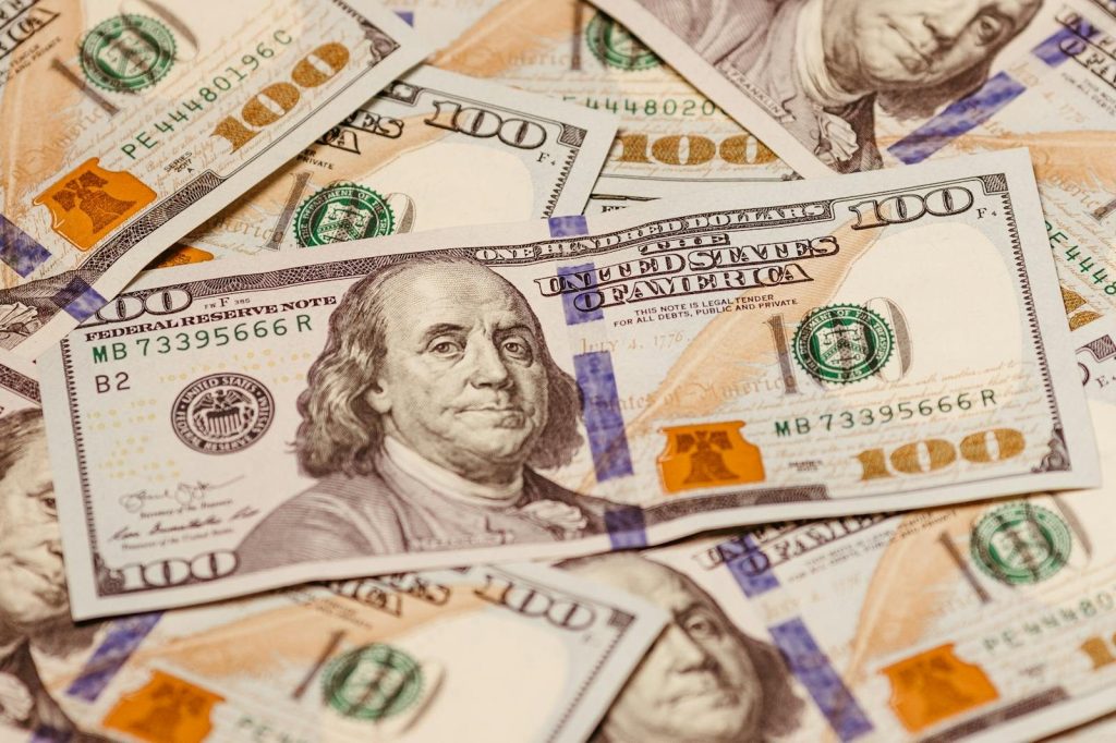 Close-up view of multiple US hundred dollar bills showcasing Benjamin Franklin.