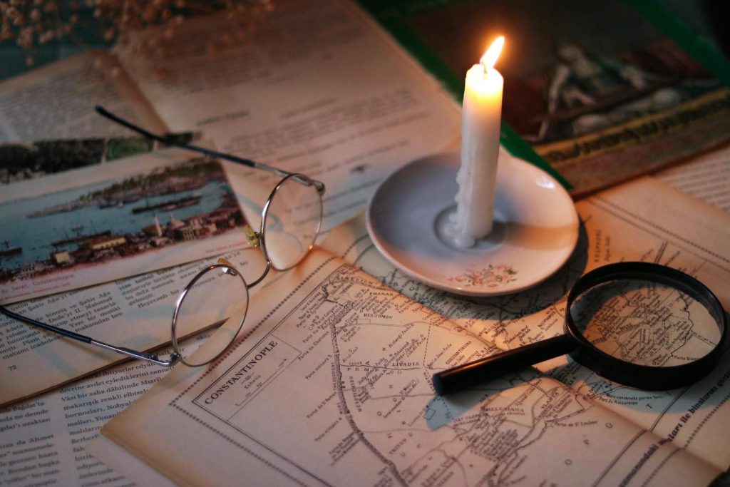 Cozy vintage scene with candle, map, glasses, and magnifying glass.