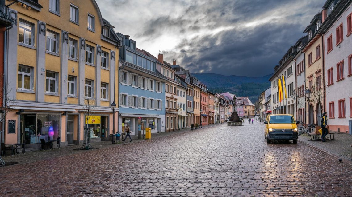Picturesque European street scene with colorful buildings, cobblestones, and a yellow van.