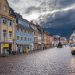 Picturesque European street scene with colorful buildings, cobblestones, and a yellow van.