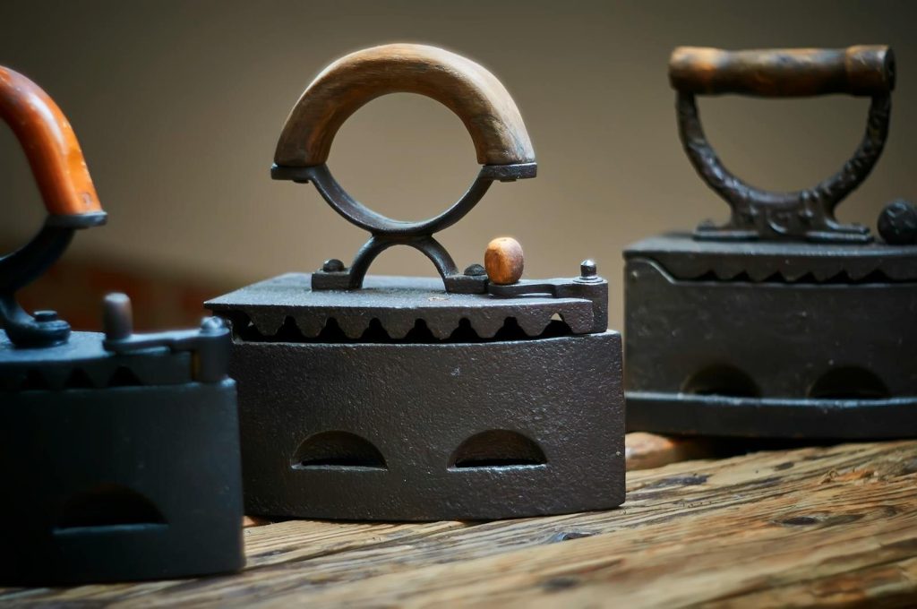 Close-up of vintage coal irons showcasing their distinctive wooden handles and antique design.
