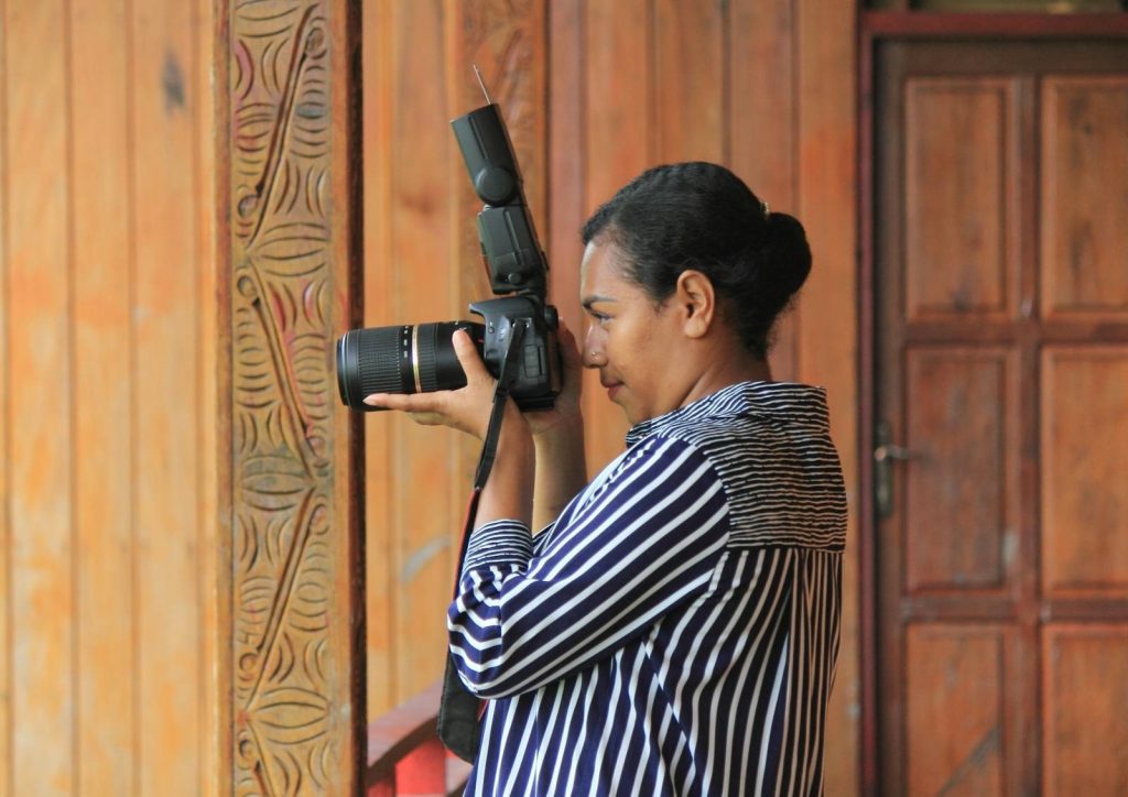 A woman photographer takes a shot indoors in Agats, Papua.