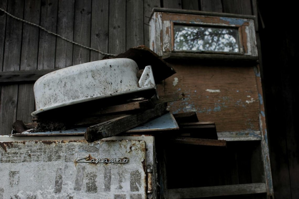 Aged and rusty appliances against a weathered wooden wall, capturing decay.
