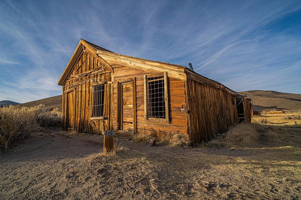 A rustic abandoned wooden house in Bodie, an old ghost town in California's desert landscape.