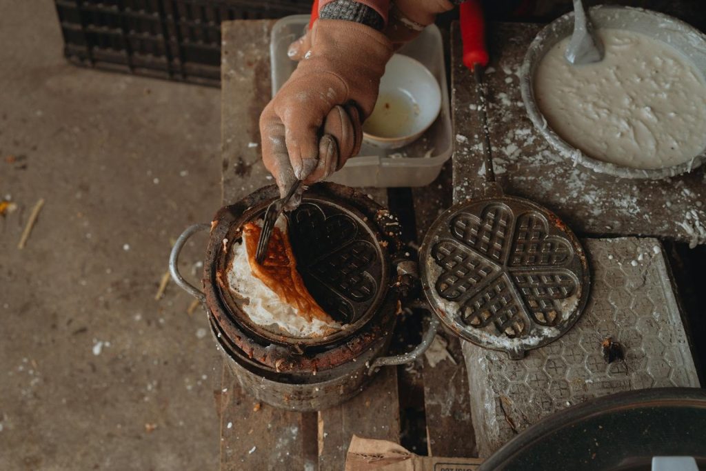 Close-up of a vintage waffle iron used in street food preparation in Bình Thuận, Vietnam.