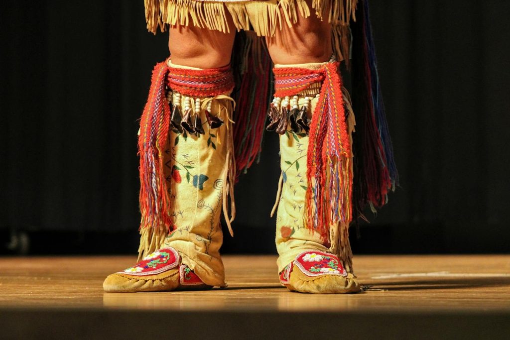 Close-up of traditional Native American dance boots with colorful patterns and fringes.