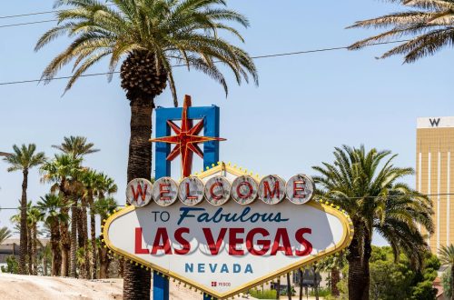 The classic 'Welcome to Las Vegas' sign amidst palm trees, under a bright blue sky.
